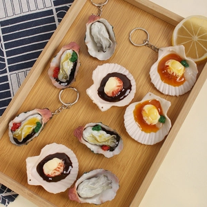 Realistic grilled oyster and scallop keychains displayed on a rustic wooden tray