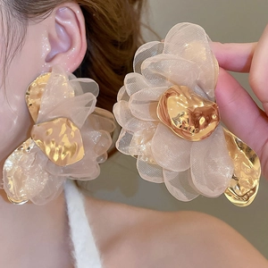 Close-up of champagne chiffon fabric flower earrings with textured gold metallic center