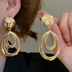 Détails de grandes boucles d'oreilles dorées ajourées en forme de goutte d'eau polie