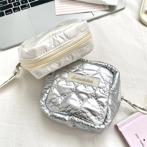 Close-up of heart-quilted PU leather mini pouches in pearl white and metallic silver colors