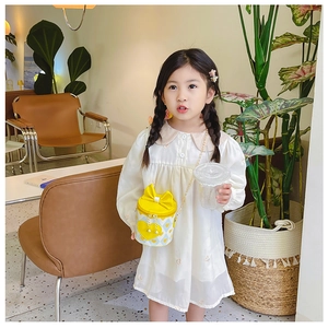 Detail of yellow round kids crossbody bag with bow and golden chain strap on a child