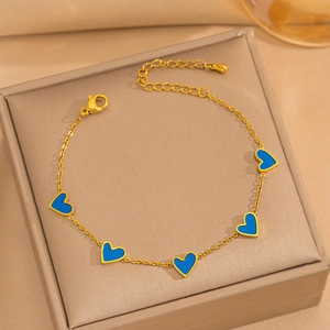 Detail of gold chain bracelet with five blue heart charms on a jewelry display box