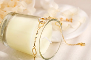 Close-up of gold stainless steel bracelet with interlocking CZ diamond rings on a candle