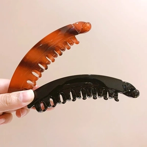 Dettaglio di fermagli a banana neri e ambra con denti interni per capelli