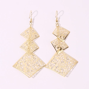 Macro detail of gold layered geometric hollow butterfly earrings with intricate patterns