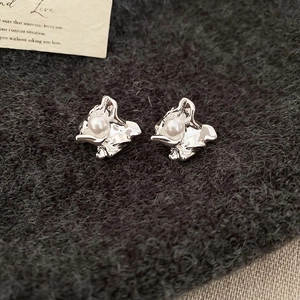 Detail of silver geometric lava earrings with white pearls on dark grey fabric