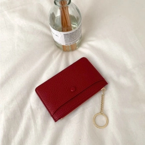 Detail of dark red cross-grain leather card holder with snap closure and gold key ring