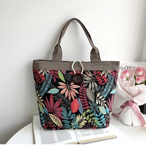 Detail of canvas tote bag with leaf pattern, corduroy trim, and large wooden button