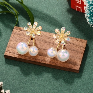 Detailed view of floral gold earrings with sparkling rhinestones and iridescent pearls