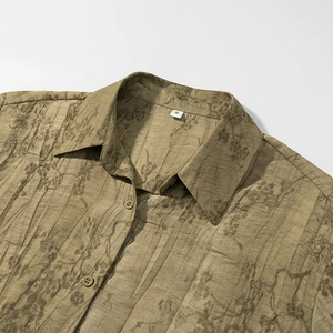 Close-up of olive brown jacquard shirt fabric with floral texture and button detail