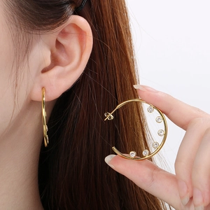 Detail of C-shaped stainless steel earrings with sparkling round cubic zirconia