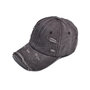 Detailed close-up of distressed vintage denim baseball cap with torn edges and worn texture