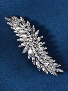 Detail of silver feather hair clip with sparkling crystals on dark blue background