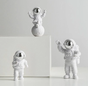 Detailed view of three white astronaut figurines with silver visors on a white display stand
