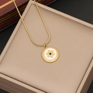 Close-up of golden necklace with green gemstone and white enamel pendant on jewelry box