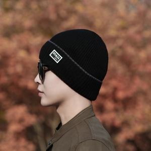 Classic black ribbed knit beanie with fashion patch on model in autumn outdoor setting