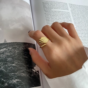 Detail of a golden shell textured adjustable ring worn by a model on a magazine