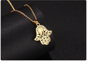 Macro detail of the back view of a gold-plated Hamsa Hand pendant with hollow patterns