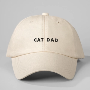 Detailed close-up of CAT DAD embroidery on a beige cotton twill baseball cap