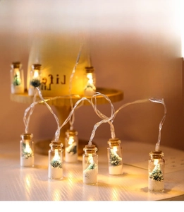 Detail of LED glass wishing bottles with mini Christmas trees and warm glowing lights