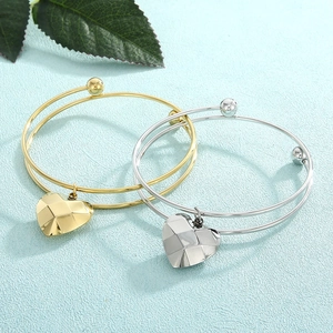 Detail of double-layer stainless steel bracelets with geometric heart pendants in gold and silver