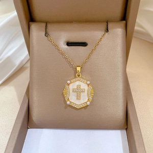 Macro shot of gold pendant with crystal hexagon frame, pearl base and paved cross