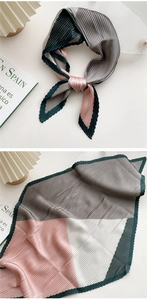 Macro shot of pleated silk scarf with green, grey, and pink geometric color blocking