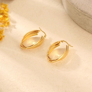 Vue détaillée de boucles d'oreilles dorées multicouches sur un fond texturé avec des fleurs