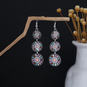 Detail of bohemian silver drop earrings with multi-colored enamel floral patterns