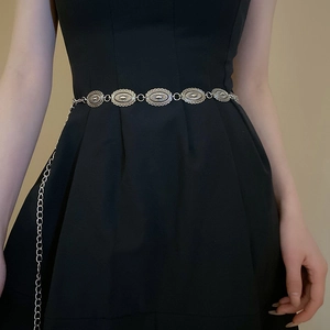 Silver metal chain belt with oval retro links worn over a minimalist black dress