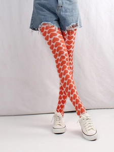 Detail shot of white patterned tights featuring vibrant red heart motifs on a model