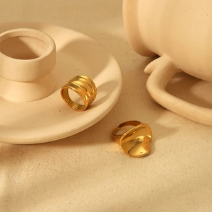 Detail of minimalist gold irregular rings with textured surfaces on cream aesthetic decor