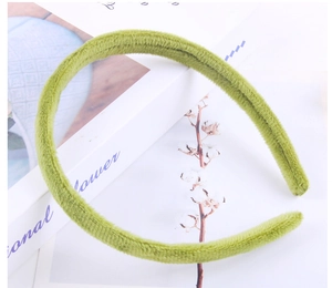 Detail of green plush velvet headband placed next to cotton branch and books
