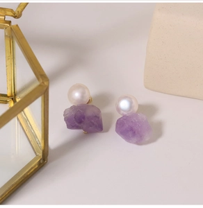 Detailansicht der Ohrringe mit Naturperle und Amethyst auf einer Glasbox-Deko