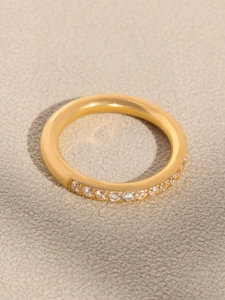 Close-up of gold-plated geometric ring featuring a half-band of inlaid clear zircon stones
