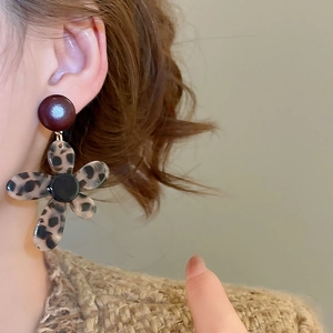 Detail of vintage leopard print flower earrings with deep red studs on model