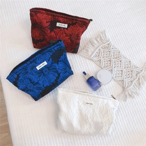 Detail of jacquard makeup bags with 3D floral patterns in red, blue and white colors