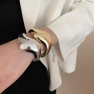 Dettagli di bracciali ondulati irregolari oro e argento con finitura a specchio lucida