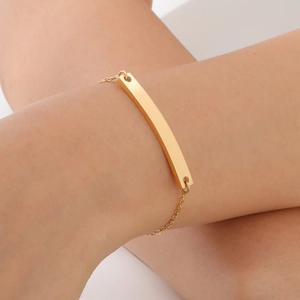 Detail of 18K gold-plated stainless steel rectangular bar bracelet on woman's wrist