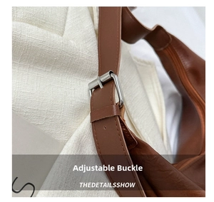 Detail of brown leather handbag strap with adjustable silver metal buckle and neat edges