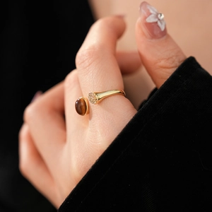 Vue détaillée de la bague dorée ouverte avec œil de tigre et oxydes de zirconium