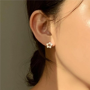 Close-up of minimalist 925 sterling silver flower stud earring worn on model ear