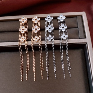 Detail of 18K gold plated clover tassel earrings with clear zircon on silk background