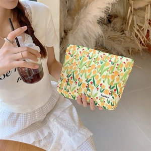 Close-up of canvas makeup bag with tulip floral print and stitched brand logo label