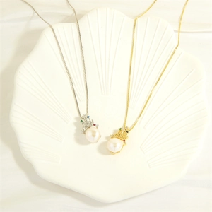Close-up of gold and silver crown necklaces with freshwater pearls on shell stand