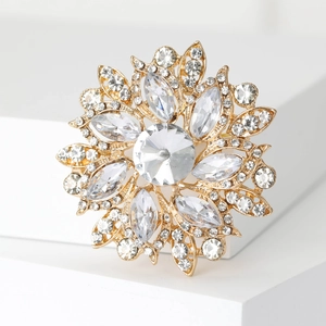 Macro shot of gold floral brooch featuring sparkling crystal petals on a white stone base