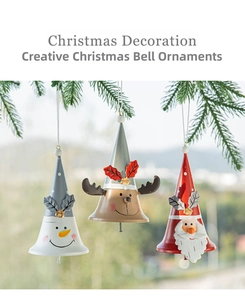 Close-up of three painted metal bells with snowman, reindeer and Santa on a pine tree