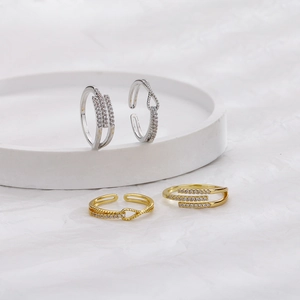Close-up of gold and silver plated knot rings with cubic zirconia pavé on a white tray