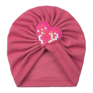 Détail du turban rose foncé pour bébé avec un écusson cœur brillant en paillettes