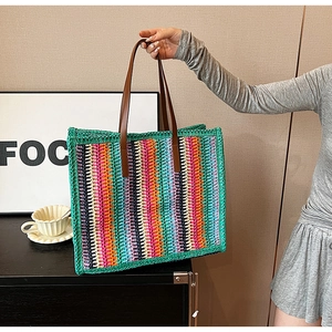 Detail of colorful striped woven tote bag featuring premium brown leather handles